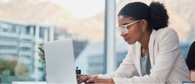 A person in a white jacket and glasses working on a computer.