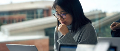 Person, die in einer Büroumgebung vor einem Laptop sitzt.