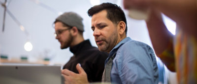 ผู้ชายสองคนอยู่ในสํานักงาน คนหนึ่งโฟกัสไปที่แล็ปท็อปและอีกคนหนึ่งกําลังสนทนา