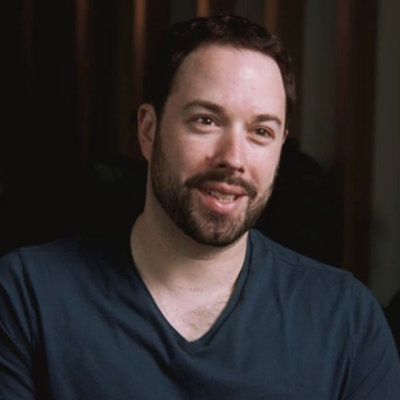Close-up portrait of a person with short hair and beard, facing slightly sideways.