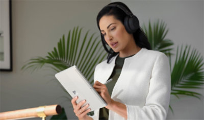 A woman wearing headphones and using a tablet