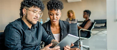 A man and woman looking at a tablet.
