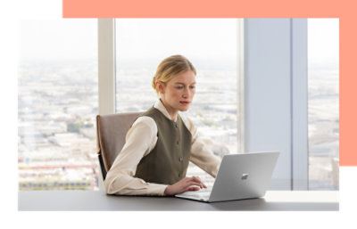 一位女士坐在办公桌前使用笔记本电脑。