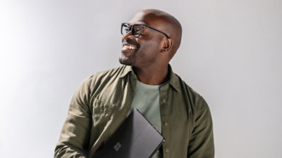 一位戴着眼镜、手持笔记本电脑微笑的男士。