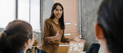 a one women standing and explaining infront of two women's.