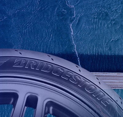 Close‑up of a vehicle wheel rim beside water with branding visible.