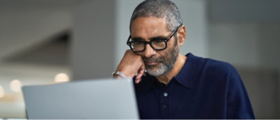 A man wearing glasses looking at a computer.
