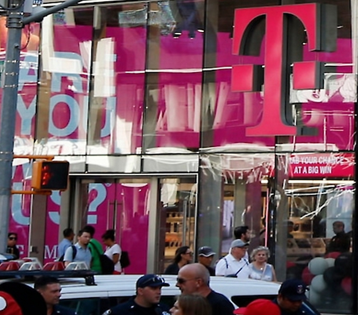Crowd outside a T‑Mobile store with a large magenta logo.