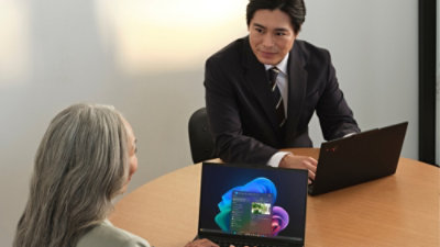 Two people seated at a table using laptops during a discussion.