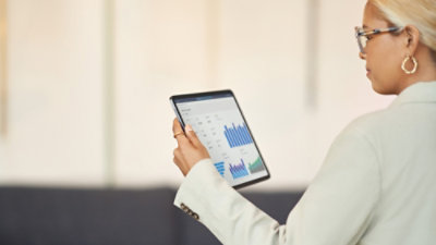 Person holding a tablet displaying bar charts and analytics.