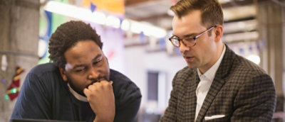 A man with his hand on his chin and other man with the glasses.
