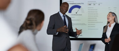 A man in a suit and tie standing in front of a projection screen.