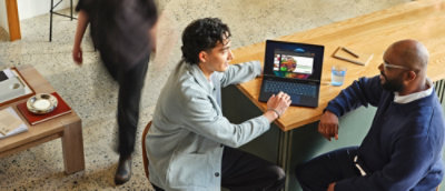Two persons sitting at a table with a laptop.
