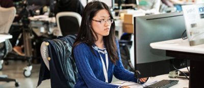 Person working at a computer in an open office environment.