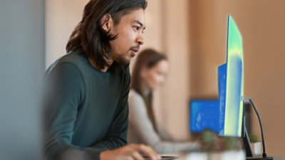 Person working at a desktop computer in an office, with another workstation in the background