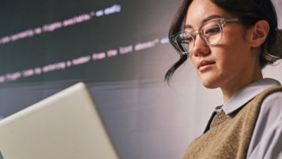 A person wearing glasses is looking at a laptop screen.