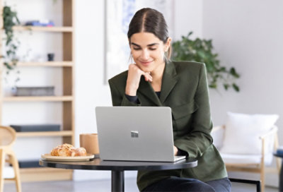 A person in a green outfit using a laptop at a table.