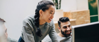 A women and a man smiling looking at their PCs