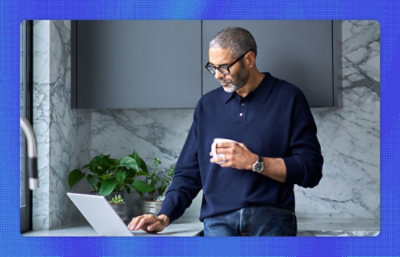 A man holding a cup and using a laptop.