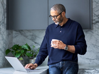 A man holding a cup and using a laptop.