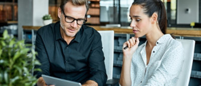 A man and woman looking at a laptop.