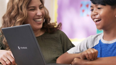 A woman smiling at a laptop.