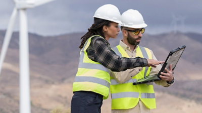 A man and woman wearing safety vests and helmets.