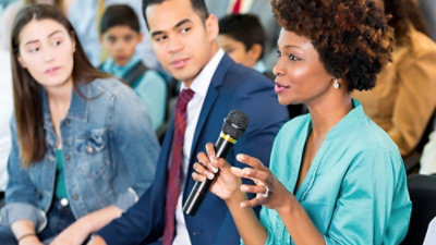 A woman holding a microphone and talking to a man.