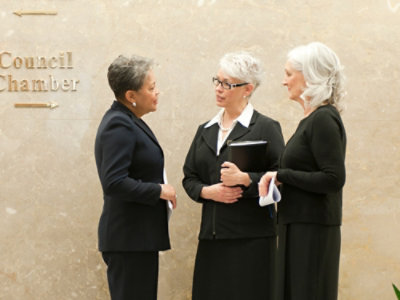 Three women wearing suits and discussing