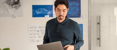  man with a mustache and beard looking down in front of a blue sign.