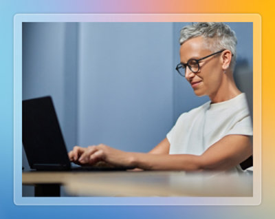 Colleagues working together at a desk with a laptop in a modern office.