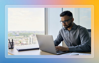 Person working on a laptop at a desk near a window.