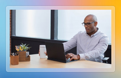 Person using a laptop at an office desk with a coffee mug.