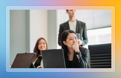 Team seated in a meeting room listening to a presenter while working on laptops.