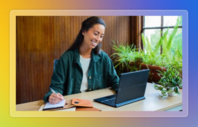 Person taking notes while working on a laptop.