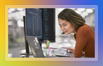 Three employees discussiing something while looking at a laptop.