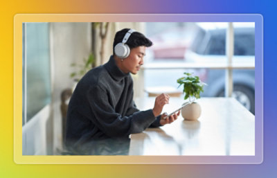 A man wearing a headphone looking at a mobile sitting a table.