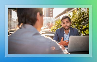 A man sitting at a table with another man in a suit.