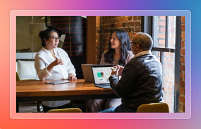 Three people discussing data on a laptop at a table.