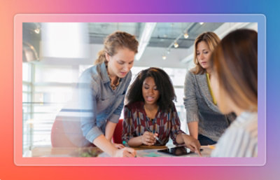 Three people collaborating around a tablet at a table.