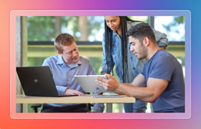 Three colleagues collaborating around a tablet and laptop during a discussion.