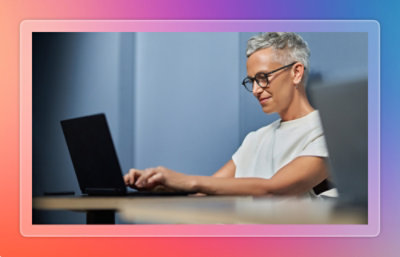 Person working on a laptop at a desk in a softly lit workspace.