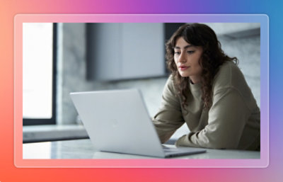 Person using a laptop while seated at a kitchen counter in a modern home environment.