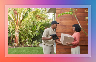 Delivery worker handing a package to a customer at the entrance of a modern home with greenery in the background.