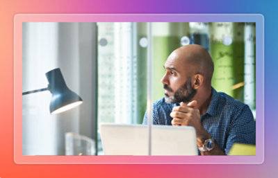 A man sitting at a desk looking at a laptop.
