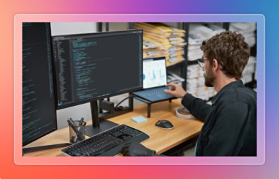 Developer working at a desk with multiple monitors displaying code and charts.