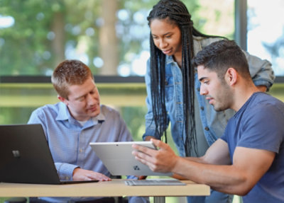 A group of people looking at a tablet.