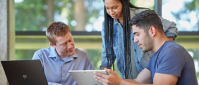 Small group collaborating around a laptop and tablet in an office setting