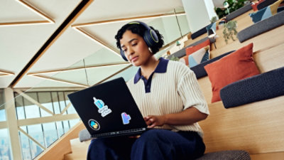 Person seated in tiered seating using a laptop in a contemporary workspace.