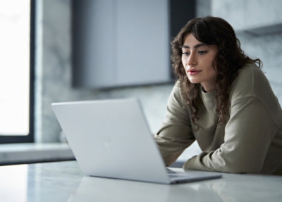 Person using a laptop at a table near a window.